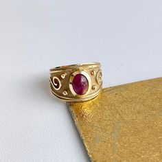 Estate/ vintage 14KT yellow Gold Byzantine/ Etruscan design polished + textured matte finish cigar band ring with genuine ruby. Elegant, old world piece with faceted, oval-shaped, cabochon, genuine red ruby. Ruby measures: 8mm x 5.7mm Size 7 Can be sized by your local jeweler or ours for a fee Solid Measures: 13.6mm wide~ graduated back to 3.5mm Weight: 4.6 grams Excellent condition Red Ruby, Cigars, Rings Statement, Band Ring, Old World, Band Rings, Statement Rings, Ruby, Jewelry Rings