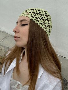 a woman with long hair wearing a crochet headband and looking down at the ground