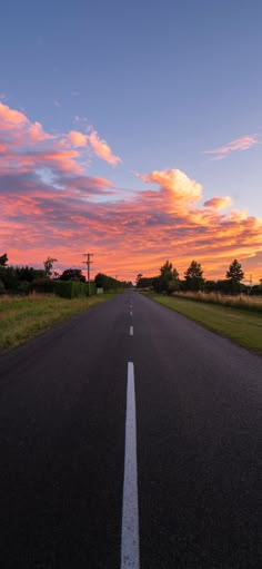 an empty road with the sun setting in the background