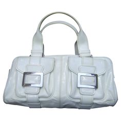 Roger Vivier Paris white patent leather chrome buckle Italian handbag c 1990s The stylish handbag is designed with a pair of flap covered chrome buckle pockets on the front exterior/ The pair of sleek chrome metal buckles are engraved with Roger Vivier's R.V. script initials Carried with a pair of matching white patent leather handles. The interior is lined in black fabric with a center divided zippered compartment. Designed with another zippered compartment with a chrome metal zipper pull engra Modern White Satchel With Palladium Hardware, Formal White Satchel With Palladium Hardware, Modern Rectangular Satchel With Silver-tone Hardware, White Bags With Buckle Closure For Everyday Use, White Formal Satchel With Silver-tone Hardware, White Satchel With Silver-tone Hardware For Formal Occasions, White Shoulder Bag With Palladium Hardware For Office, White Satchel With Silver-tone Hardware For Office, White Shoulder Bag With Silver-tone Hardware For Office