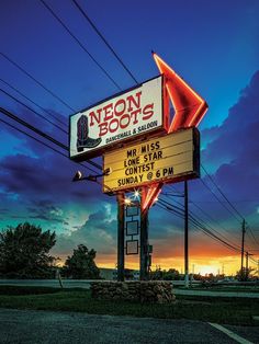 the neon sign for neon boots is lit up at dusk with power lines in the background