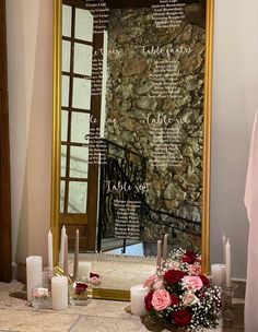 a large mirror sitting on top of a bathroom counter next to candles and vases