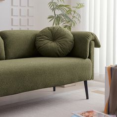 a green couch sitting on top of a white floor next to a potted plant