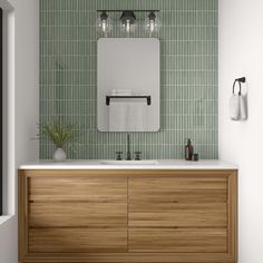 a bathroom with green tiled walls and wooden cabinetry, two mirrors above the sink