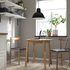 a small table with two chairs and a laptop on it in front of a window