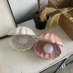 three seashells sitting on top of a table next to a potted plant