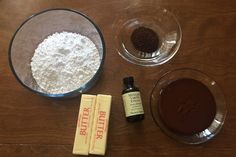 ingredients to make chocolate cake sitting on top of a wooden table next to a bowl