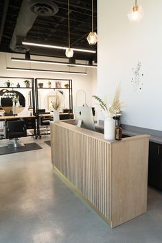 the front desk of an office with plants in vases sitting on top of it