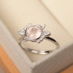 a close up of a ring in a box with a pink stone and diamonds on it