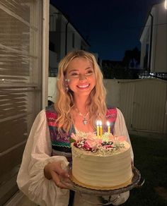 a woman holding a cake with lit candles