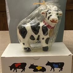 a cow figurine sitting on top of a box with plastic wrap around it's neck