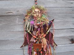 a woman's head is made out of different colored beads and other things hanging from the wall