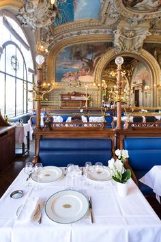 a dining room with blue booths and white tablecloths on the tables, along with large windows