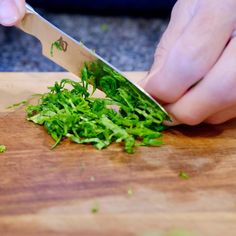 someone is cutting up some greens on a wooden board