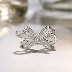 Give her all your love tied up with a glistening bowknot ring. It features a ribbon that twists and twirls into a charming bow at the center. Standing atop a polished shank, this lovely design makes an elegant accessory. Sparkling stones add an element of glamour to this feminine design.Carat Weight: 0.97 ctStone Size: 1.1,1.2 mmStone Type: Jeulia® StoneNumber of Stones: 78 Stone Color: Diamond WhiteStone Shape: RoundWeight: 4.79 gWidth: 14.2 mmHeight: 8.3 mmThickness: 2.5 mmMaterial: 925 Silver Diwali Jewellery, Bow Fashion, Silver Cocktail, Bow Ring, Bow Jewelry, Silver Jewellery Sets, Fine Jewelery, Feminine Design, Elegant Accessories