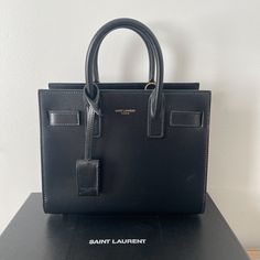 Saint Laurent Handbag Black Never Worn!! Have Dust Bag And Box ! Rectangular Bags With Branded Hardware, High-end Rectangular Satchel With Branded Hardware, Designer Rectangular Satchel With Branded Hardware, High-end Luxury Tote Bag, High-end Satchel Tote With Branded Hardware, High-end Tote Bag With Branded Hardware, Designer Box Bag With Branded Hardware For Daily Use, High-end Black Rectangular Bags, High-end Square Bags With Branded Hardware