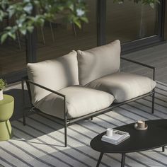 a couch sitting on top of a wooden floor next to a table and potted plant