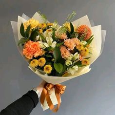 a person holding a bouquet of flowers with orange and white blooms in it's hands