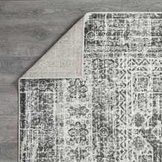 two rugs on the floor, one with an area rug in grey and white