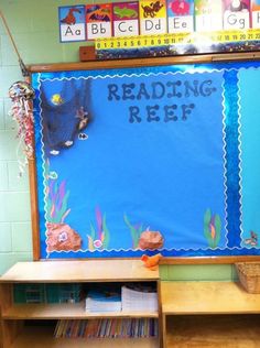 a bulletin board with reading reef written on it in front of a classroom desk and bookshelf