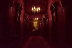 a long hallway with chandeliers and lights on either side of the corridor is lit up at night