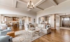 a living room filled with furniture and a chandelier hanging from the ceiling over a wooden floor