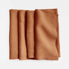 three folded linen napkins on top of each other, one in brown and the other in tan