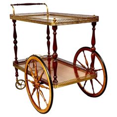 an antique wooden cart with wheels and wood trimmings on the sides, sitting against a white background