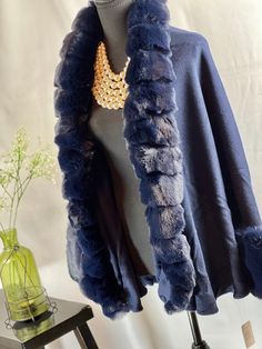 Upgrade your winter wardrobe with this chic navy blue cape. Made from a luxurious blend of wool and acrylic, it features a stylish faux fox fur trim that wraps around the neck and cascades down the front for added warmth. The open front style adds an element of sophistication to this piece. This cape exudes elegance with its faux fur trim that gives it a high-end look. The two-tone gradient color adds a unique touch, making it the perfect accessory to wear with jeans or leggings for any occasion. The voluminous faux fur adds a layer of style and is a must-have for those cold winter months. Not only is this cape perfect for fashion outings, but it's also ideal for casual wear, holiday festivities, shopping, dates, and any evening party. You can even wear it to your prom or as a bridal cover Elegant Winter Capelet, Elegant Evening Cape For Winter, Winter Evening Capelet, Elegant Evening Winter Capelet, Elegant Evening Capelet For Winter, Elegant Winter Shawl Cape, Elegant Blue Shawl For Fall, Luxury Blue Outerwear For Evening, Elegant Blue Fall Shawl