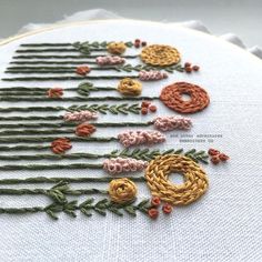 a close up of a cross stitch pattern on a white cloth with orange and yellow flowers