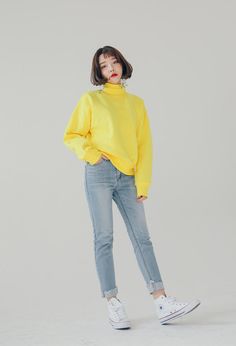 a woman in yellow sweater and jeans posing for the camera