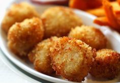 some fried food on a white plate next to carrots and ketchup sticks