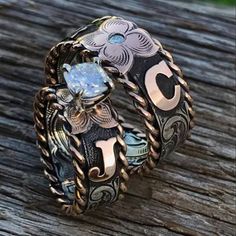 two rings sitting on top of a wooden table next to each other and one has a diamond