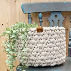 a crocheted basket sitting on top of a chair next to a potted plant