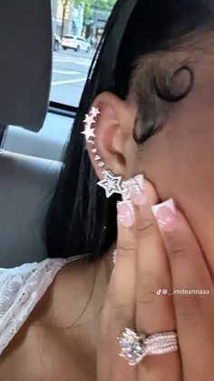 a woman with white nail polish holding her nose to the side of her face while sitting in a car