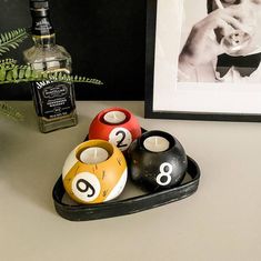 four pool balls in a tray next to a bottle of booze and a framed photograph