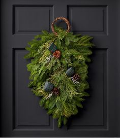 a wreath hanging on the front door with pine cones and evergreen leaves, plaid flannel