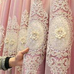 a person is touching the back of a lace curtain