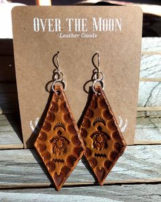 the earrings are made out of leather and have an intricate design on them, which is also