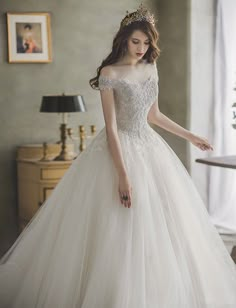 a woman in a white wedding dress is looking down at her hand on the floor