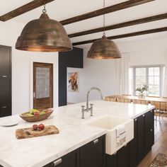 a kitchen with an island, sink and hanging lights