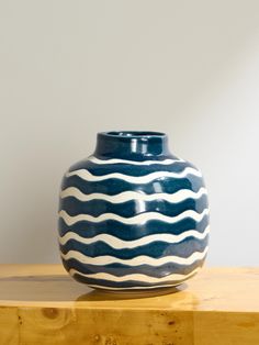 a large blue and white vase sitting on top of a wooden table next to a wall