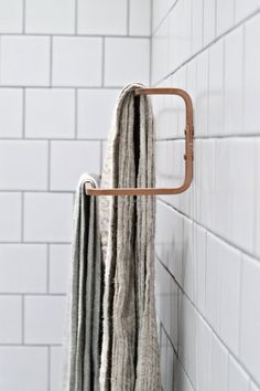 a towel rack in the corner of a bathroom with white tile walls and flooring