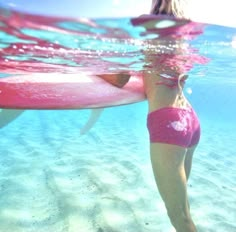 a woman in pink swimsuit holding a surfboard under water