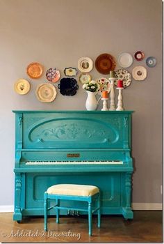 a blue piano sitting in front of a wall with plates on it