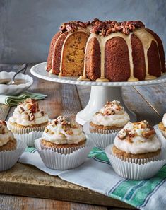 a bundt cake with frosting and nuts on top next to cupcakes