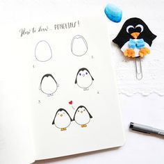 an open notebook with penguins drawn on it next to a paper clip and marker pen