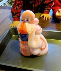 a plastic doll sitting on top of a metal tray next to a bottle of liquid