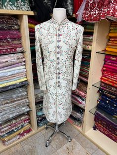 Men's Ivory sherwani with all-over blue and red thread embroidery ( French knot stitch with zardozi work). This sherwani is an easy to match with most lehengas Comes with Ivory churidars. Crafted with a collar neckline, full sleeves, and front button closure. Occasion: Can be worn to events like Wedding WASH CARE INSTRUCTIONS - Please Dry clean only when it is applicable. Slight color variation is possible due to digital photography. Cream Churidar With Floral Embroidery For Wedding, Semi-stitched Embroidered Raw Silk Sherwani, Semi-stitched Raw Silk Sherwani With Embroidery, Festive Semi-stitched Sherwani With Floral Embroidery, Traditional Long Sleeve Cream Sherwani, Traditional Cream Long Sleeve Sherwani, Cream Long Sleeve Sherwani For Transitional Season, Fitted Embroidered Cream Churidar, Long Embroidered Sherwani For Eid