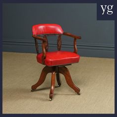 a red leather chair sitting on top of a wooden table next to a gray wall